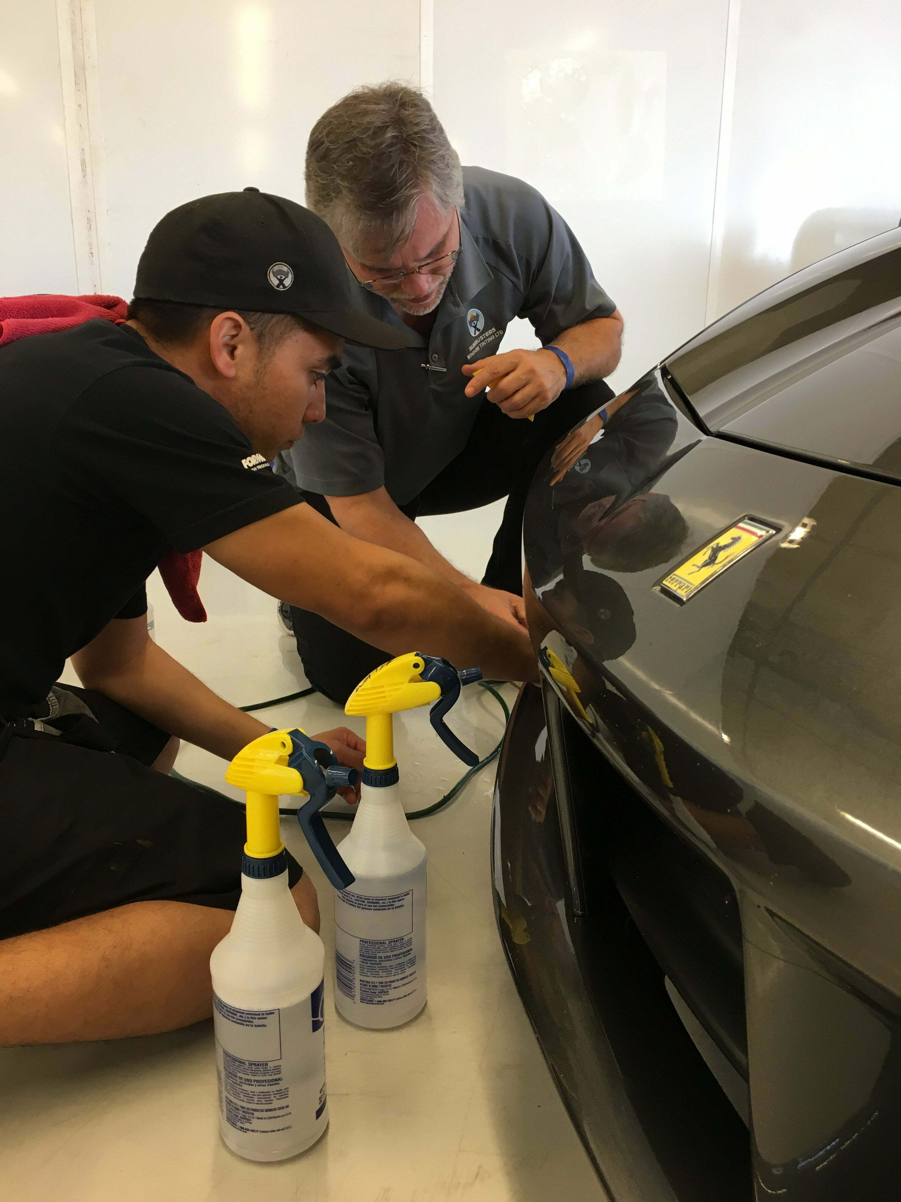 Sunbusters' professionals applying paint protection to black Ferrari